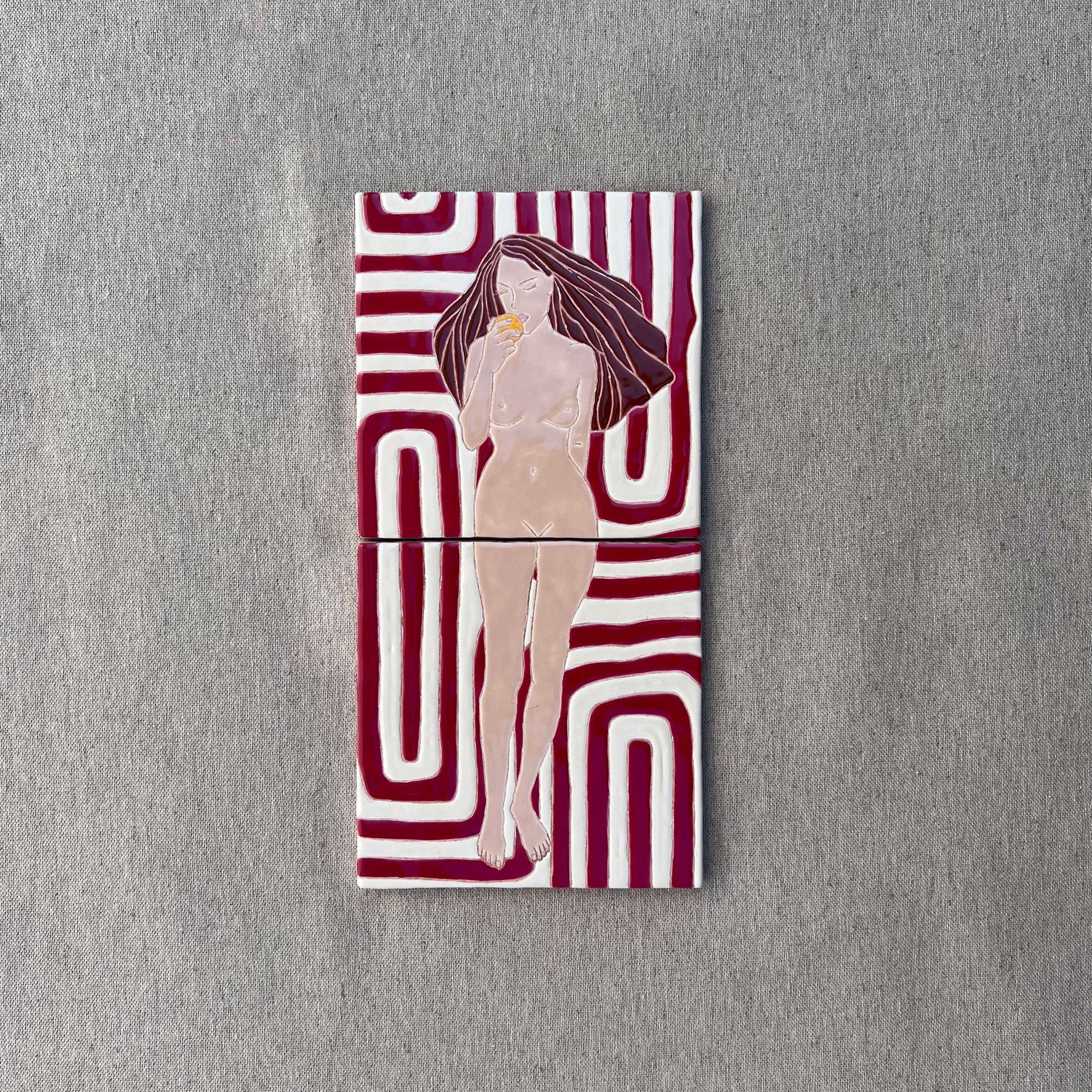 A Hand-Painted Tile Mural of a Female Nude on a Patterned Background
