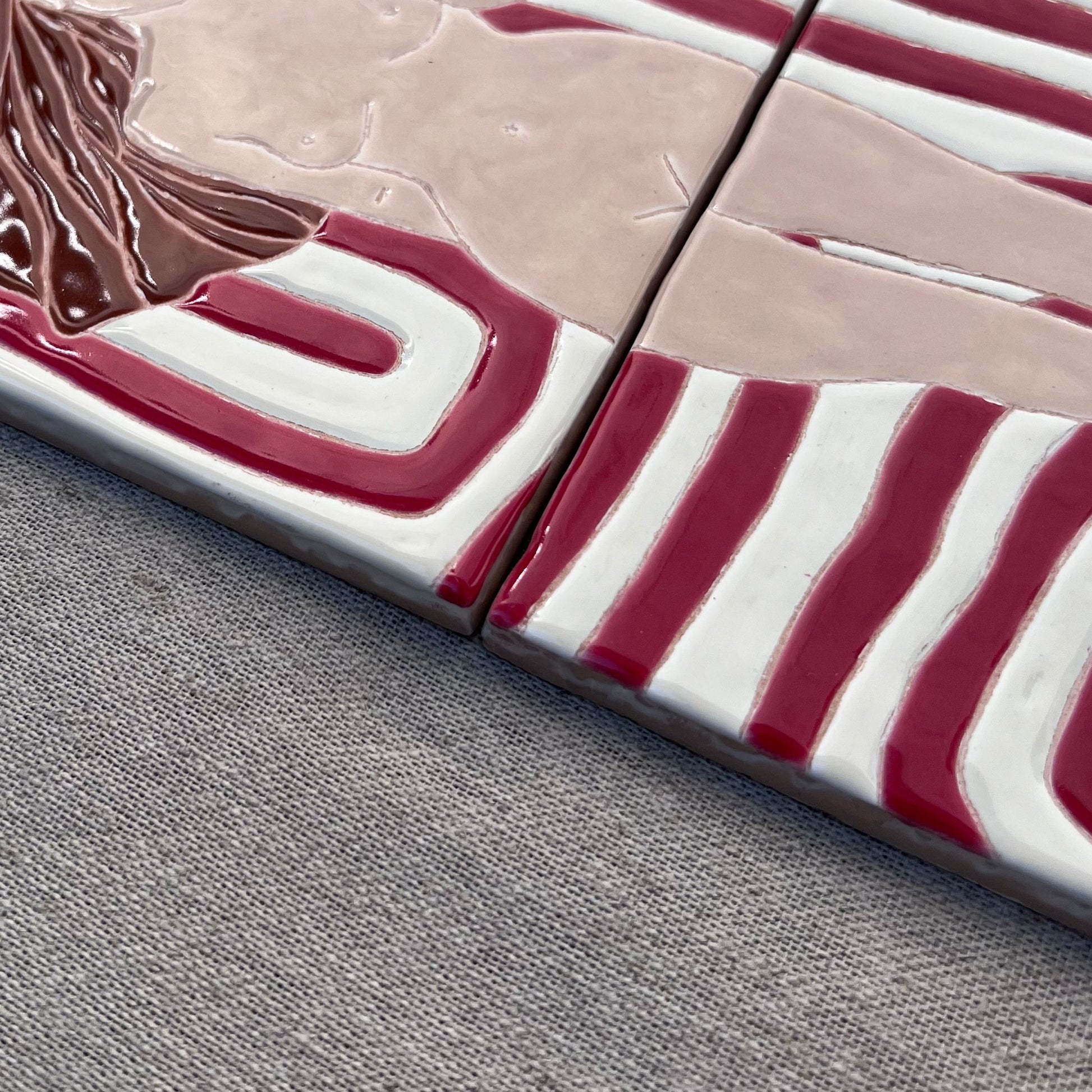 Close-Up of a Hand-Painted Tile Mural of a Female Nude on a Patterned Background